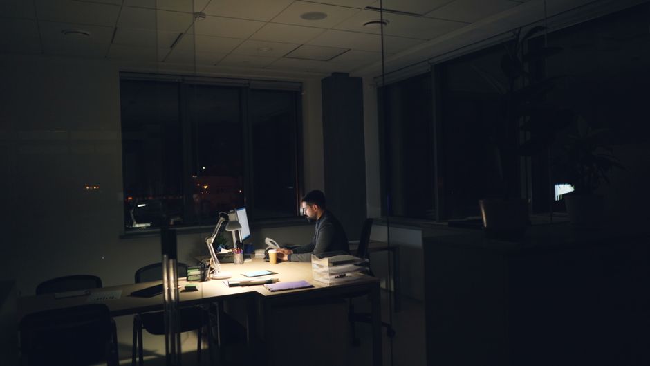 夜のオフィスで一人、事務作業に追われ続ける様子