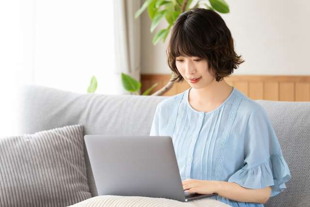 ソファでパソコンを開いて学ぶ女性