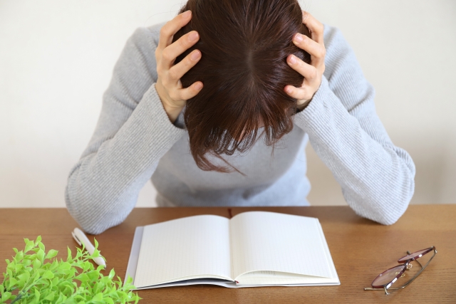 ノートを前に頭を抱える女性